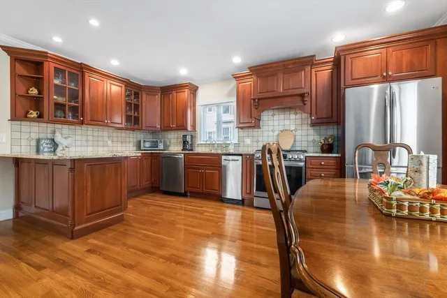 a kitchen with stainless steel appliances granite countertop wooden cabinets a dining table and chairs
