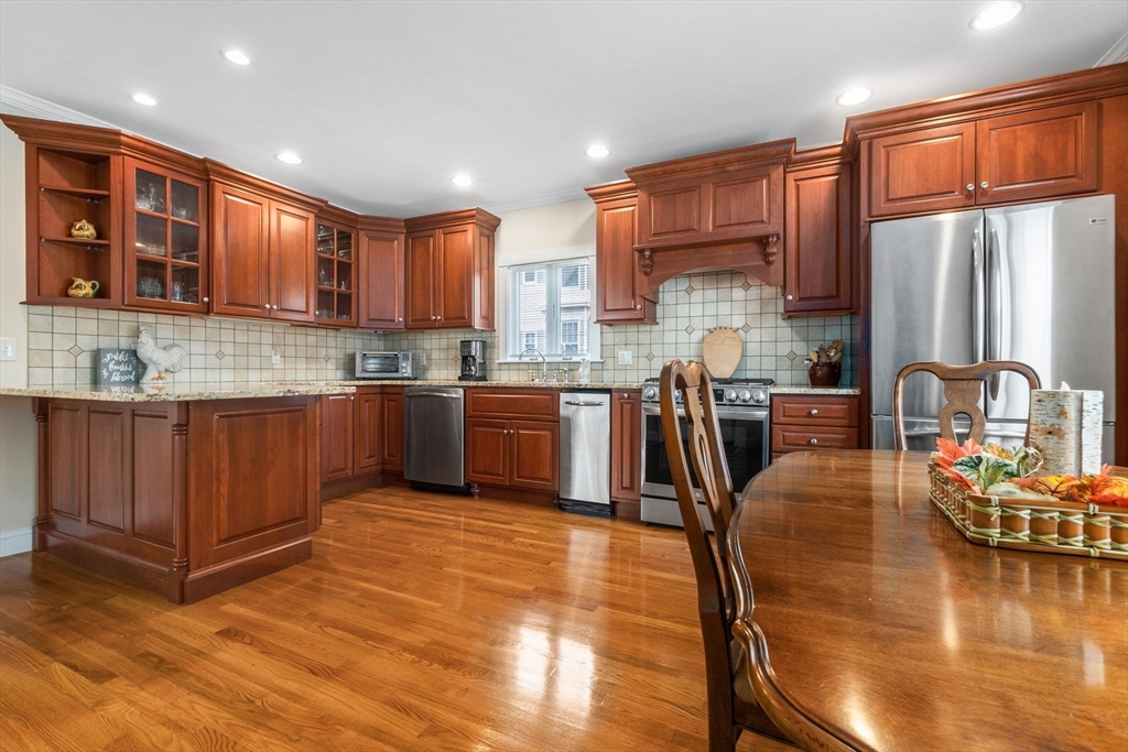 20 Ash Street, Unit 1 Danvers, MA 01923 - Photo 14 of 42 a kitchen with stainless steel appliances granite countertop a stove top oven a sink dishwasher a dining table and chairs with wooden floor