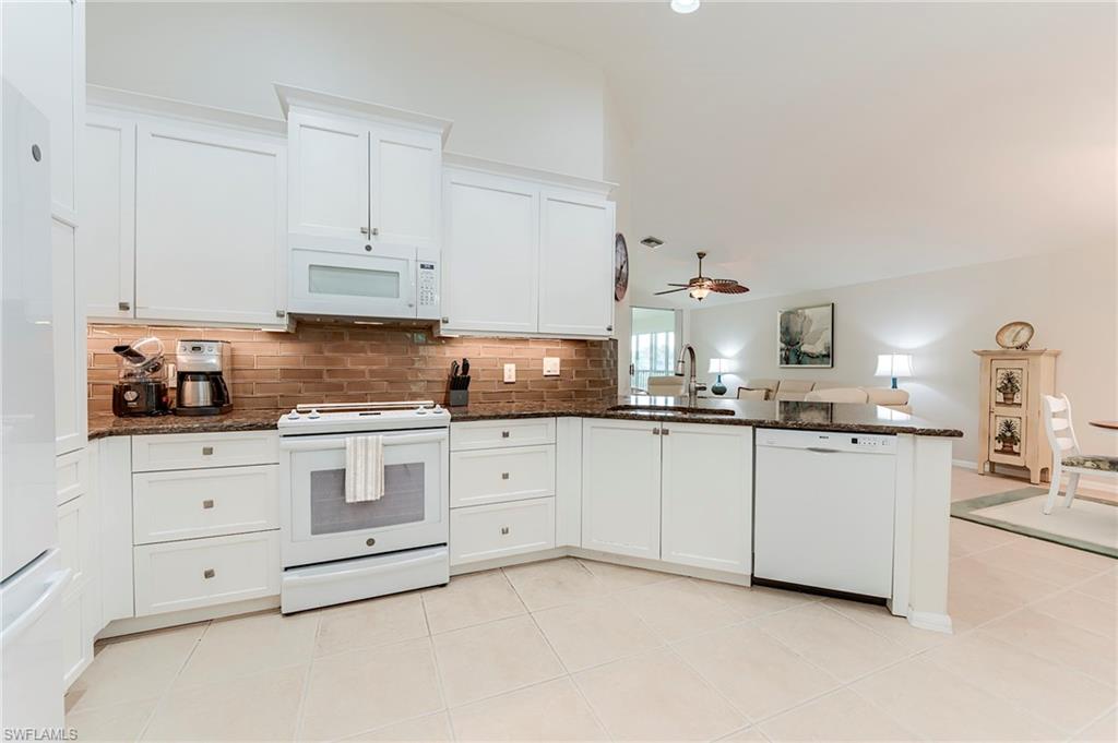 9241 Spring Run Boulevard, Unit 2202 Estero, FL 34135 - Photo 4 of 33 a kitchen with granite countertop white cabinets and white appliances