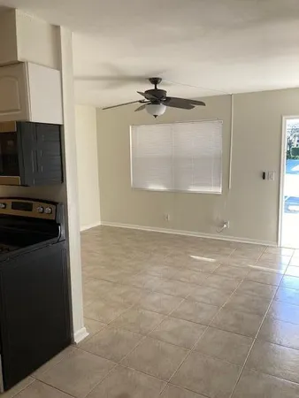 a view of a refrigerator in kitchen and an empty room