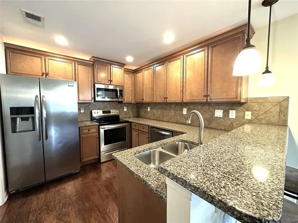a kitchen with stainless steel appliances granite countertop a sink a stove and a refrigerator