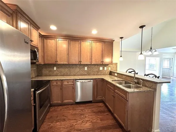 a kitchen with stainless steel appliances granite countertop a sink and dishwasher a refrigerator with wooden cabinets