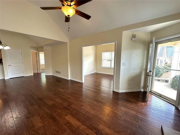 a view of an empty room with wooden floor and a window