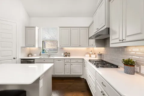 a kitchen with kitchen island granite countertop a sink a stove cabinets and counter space