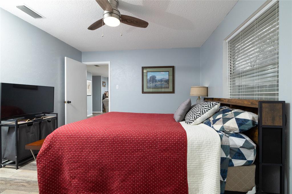 6020 Harrison Way Watauga, TX 76148 - Photo 22 of 32 Bedroom featuring ceiling fan, light wood-type flooring, and a textured ceiling