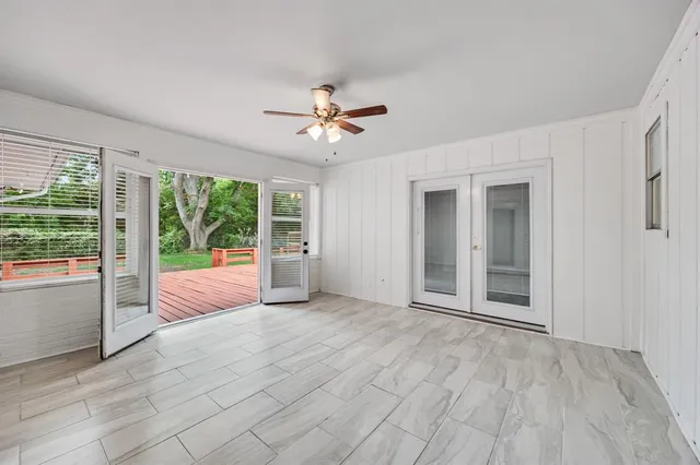 a view of an empty room with chandelier fan and wooden floor