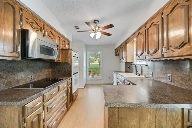a kitchen with stainless steel appliances granite countertop a sink a microwave cabinets and stove top oven