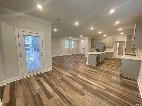 a view of kitchen with kitchen island wooden floor center island and stainless steel appliances