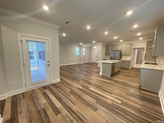 a view of kitchen with kitchen island wooden floor center island and stainless steel appliances