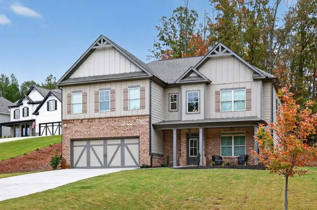 a view of a white house with a yard plants and large tree
