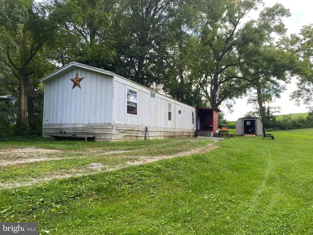 a backyard of a house with wooden fence and large trees