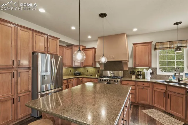 a kitchen with stainless steel appliances granite countertop a sink a stove a refrigerator cabinets and chairs