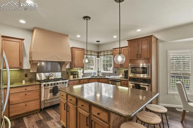 a kitchen with kitchen island granite countertop a sink a counter space appliances and cabinets
