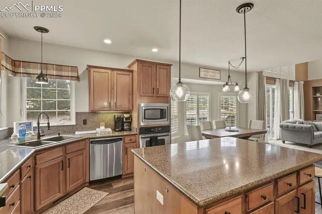 a kitchen with stainless steel appliances granite countertop a sink a stove and a wooden floors