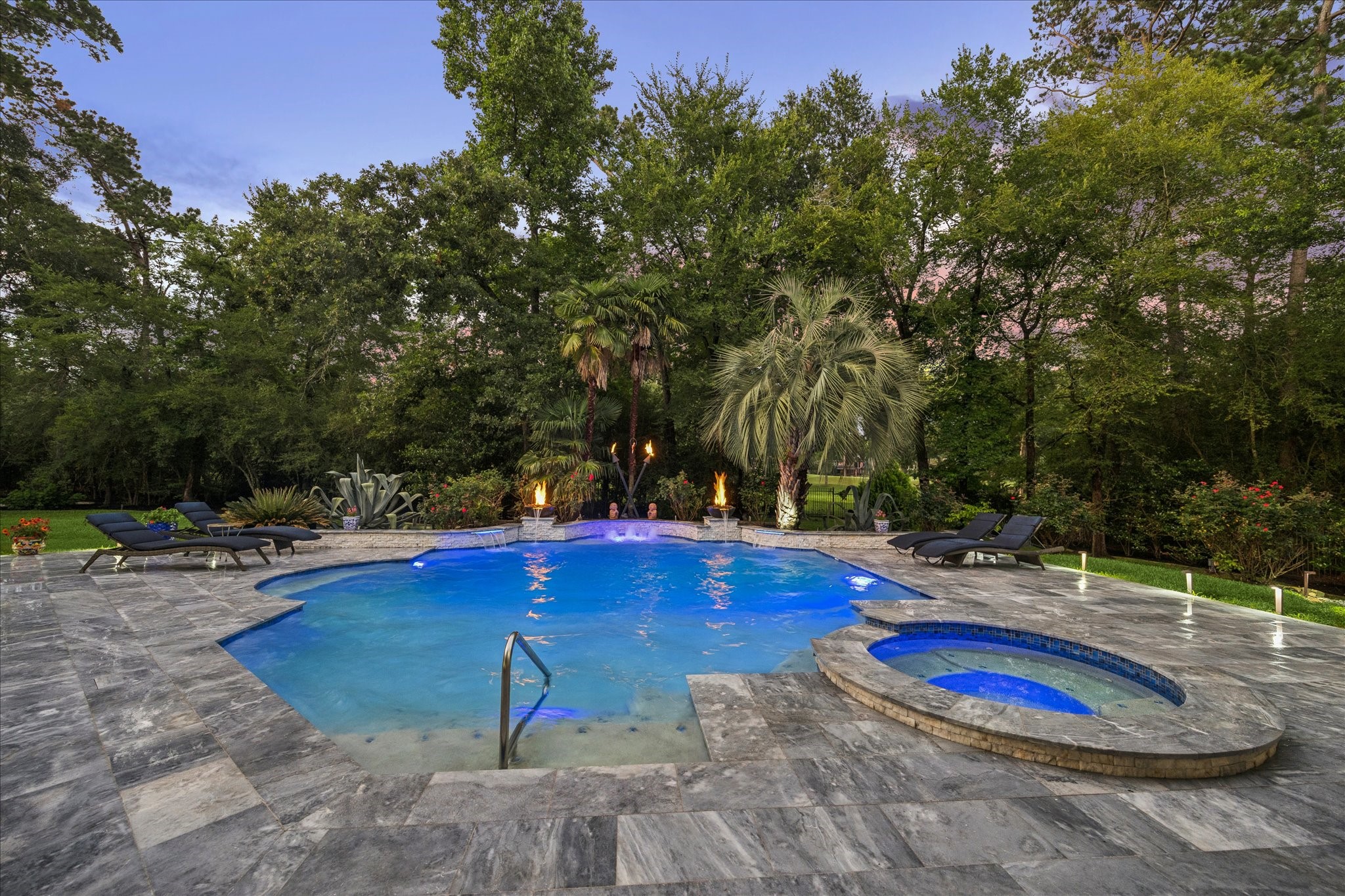 35 North Regent Oak Spring, TX 77381 - Photo 39 of 43 A resort-style backyard retreat crafted for effortless entertaining and everyday escape. Complete with a stunning pool and spa, elegant fire features, flowing waterfalls, and expansive marble decking, this outdoor sanctuary blends luxury with comfort. Lush landscaping, soft ambient lighting, and thoughtfully designed lounge spaces create an inviting atmosphere perfect for relaxing days and unforgettable nights outdoors.