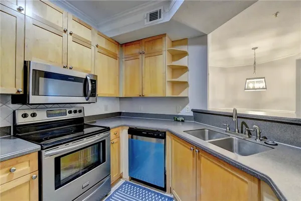a kitchen with stainless steel appliances a stove a sink a microwave cabinets and a counter space