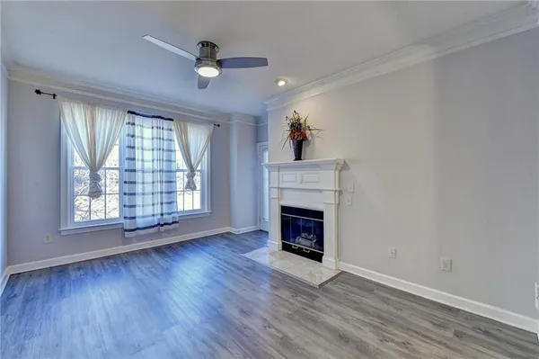 an empty room with windows a fireplace a ceiling fan and wooden floor
