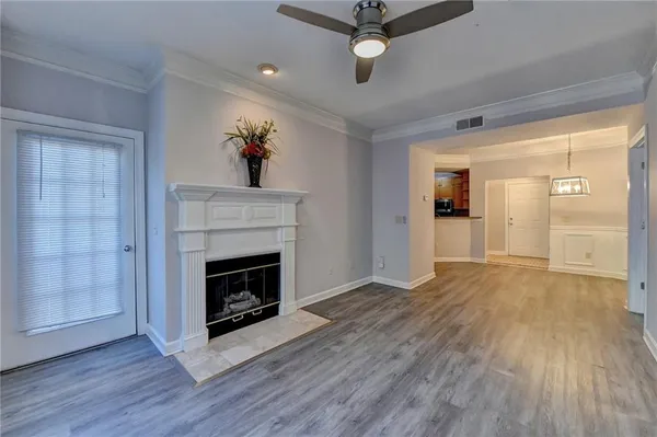 a view of an empty room with wooden floor fireplace and a window