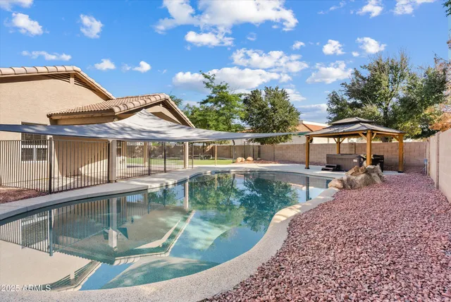 a view of a house with pool lawn chairs and a fire pit