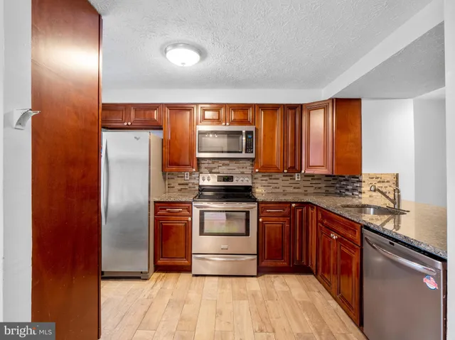 a kitchen with stainless steel appliances granite countertop a stove a sink and a refrigerator