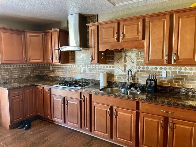 a kitchen with stainless steel appliances granite countertop a stove a sink dishwasher and cabinets with wooden floor