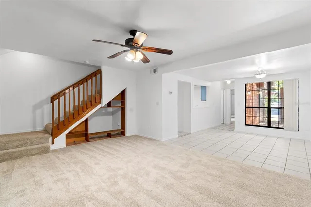 a view of an empty room with wooden floor and a ceiling fan