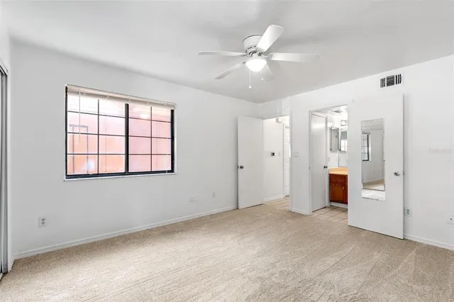 an empty room with fan and windows