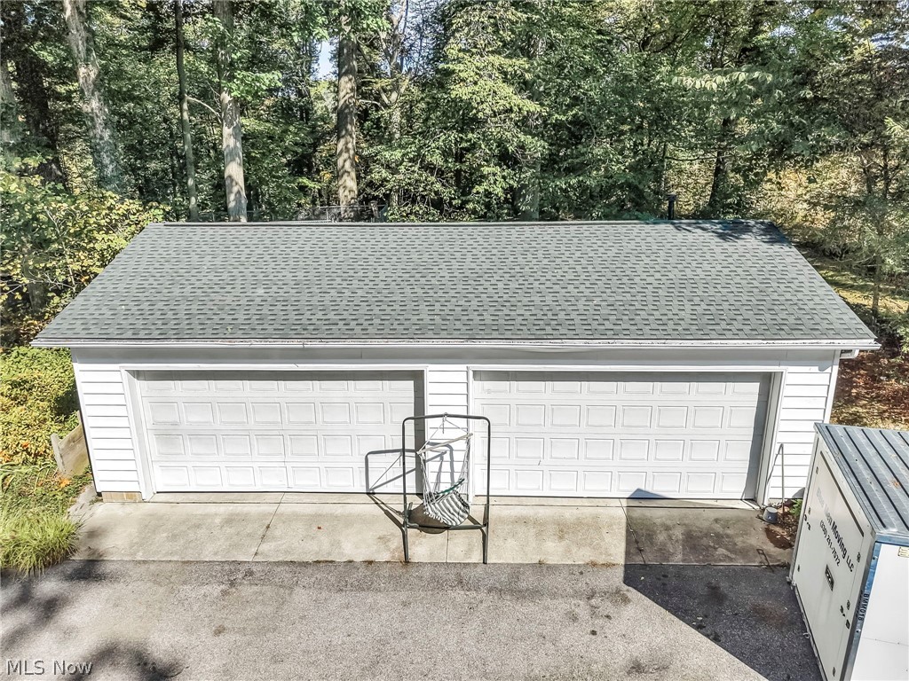 3583 West Bath Road Akron, OH 44333 - Photo 33 of 42 Four-car garage with white paneled doors, light grey shingle roofing, and white vinyl siding