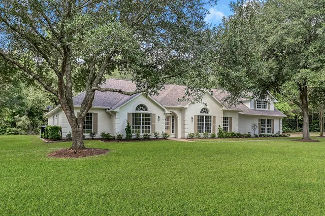a front view of a house with a garden and trees