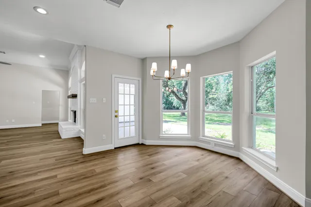a view of an empty room with wooden floor fridge and a window