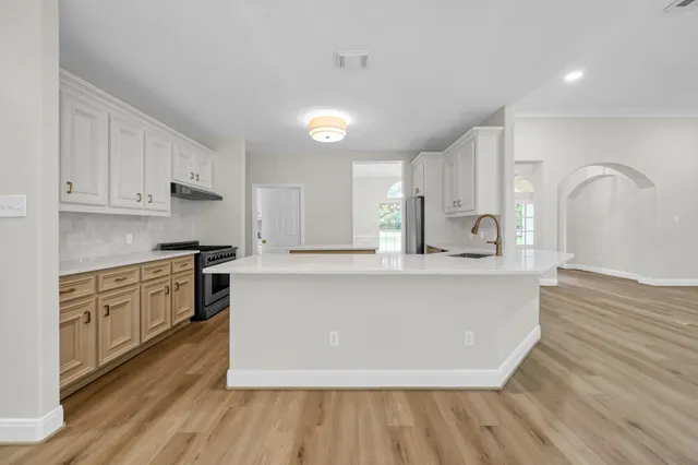 a large kitchen with kitchen island a sink wooden floor and stainless steel appliances