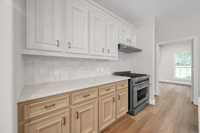 a kitchen with white cabinets and a stove with wooden floor