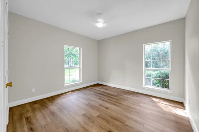 an empty room with wooden floor and windows