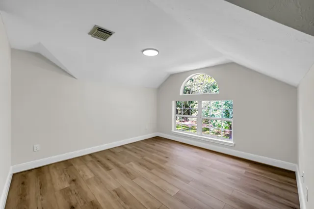 an empty room with wooden floor a ceiling fan and windows