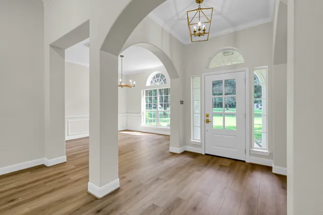 an empty room with wooden floor mirror and windows