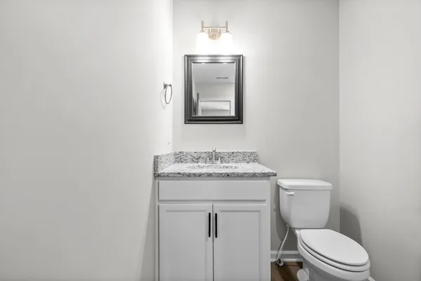 a bathroom with a granite countertop toilet sink and mirror