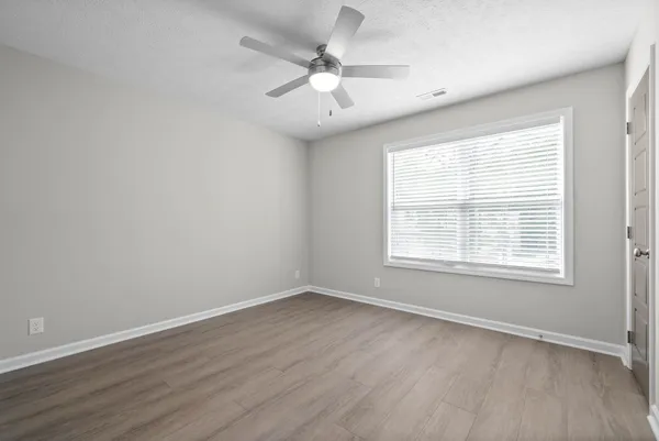 an empty room with wooden floor and windows
