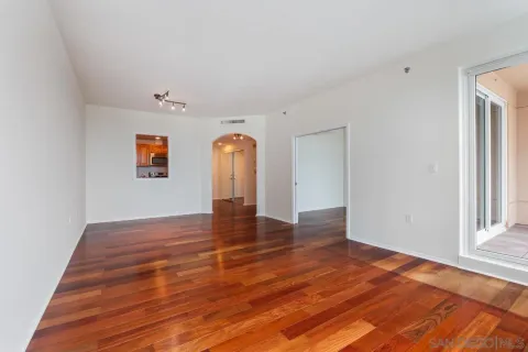 an empty room with wooden floor and windows