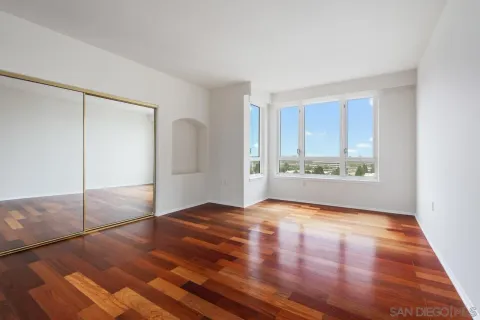 a view of an empty room with window and wooden floor