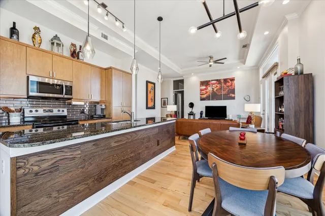 a kitchen with stainless steel appliances granite countertop a stove top oven a sink a dining table and chairs with wooden floor