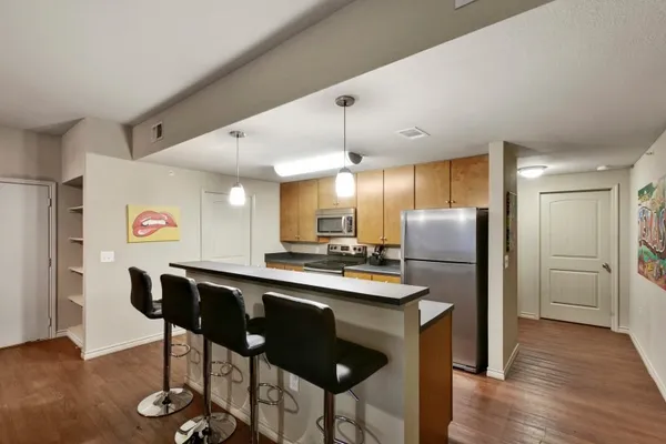 a kitchen with stainless steel appliances a dining table chairs refrigerator and sink