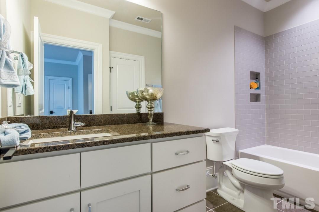 11005 Soco Gap Court Raleigh, NC 27613 - Photo 23 of 25 a bathroom with a granite countertop sink a toilet and a mirror