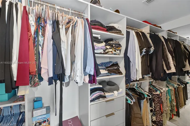 a view of walk in closet with clothes and shoes