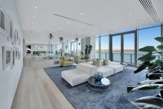 a living room with furniture potted plant a flat screen tv and a large window