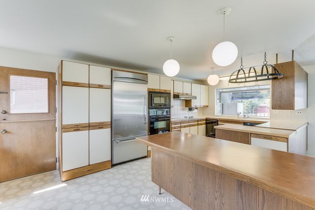 a large kitchen with a large counter top stainless steel appliances and cabinets