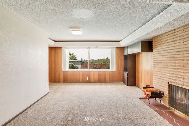 a view of an empty room with a fireplace and a window