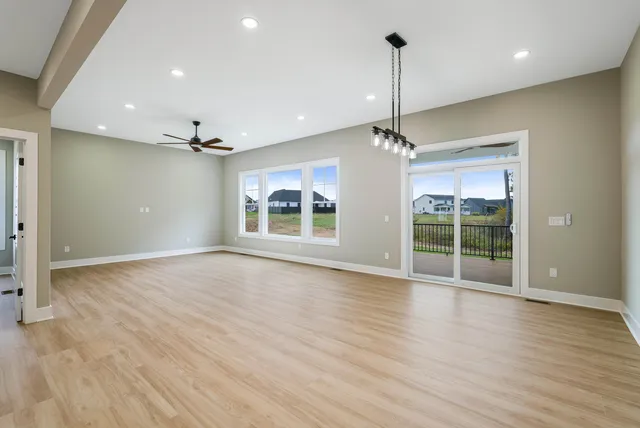 a view of a room with wooden floor a ceiling fan and windows