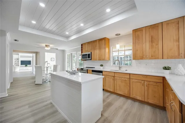 a large kitchen with a refrigerator a sink dishwasher stove and white cabinets with wooden floor