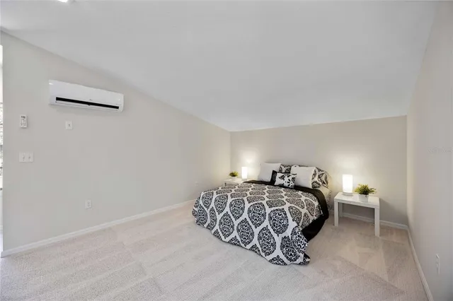 a spacious bedroom with a bed painting on wall and windows