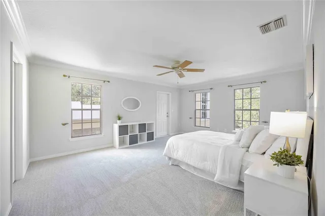 a spacious bedroom with a bed a ceiling fan and a large window